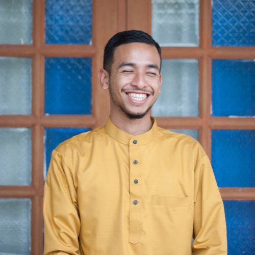 smiling-man-standing-against-window